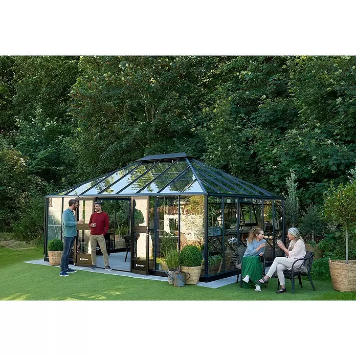 Juliana Gewächshaus Grand Oase - Material Seitenwand: Glas, 3 mm, Anthrazit - Großes Gewächshaus mit schwarzem Rahmen und Glaspaneelen im Garten, mit Leuten, die sich unterhalten.