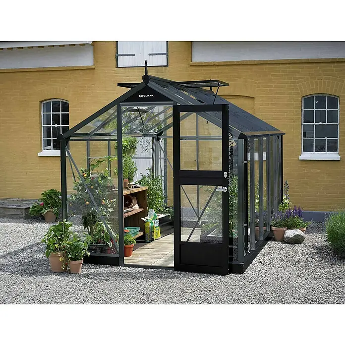 Juliana Gewächshaus Compact - Außenmaß inkl. Dachüberstand (B x T): 224 x 368 cm, Material Seitenwand: Glas, 3 mm, Schwarz - Ein geräumiges Juliana Gewächshaus mit Pflanzen und Gartenutensilien, das eine einladende Atmosphäre für Gartenliebhaber schafft.