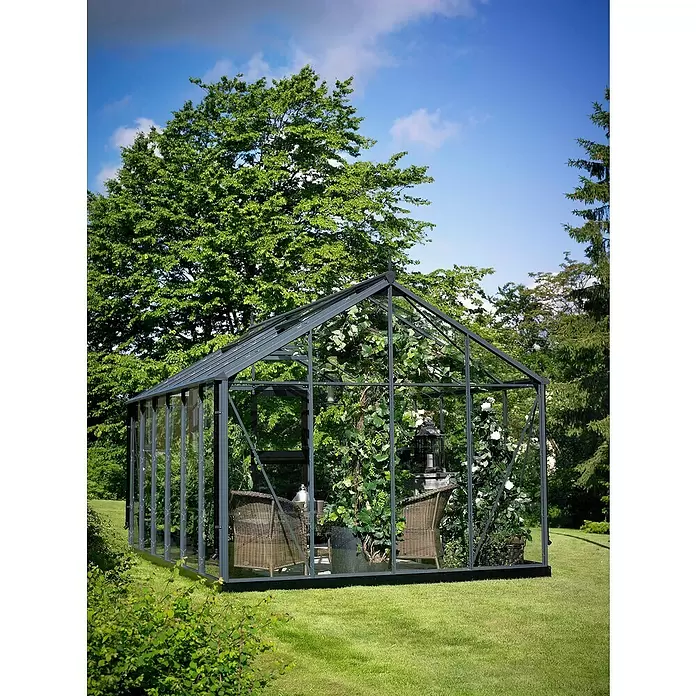 Juliana Gewächshaus Premium - Außenmaß inkl. Dachüberstand (B x T): 296 x 439 cm, 3 mm, Anthrazit, Einscheibensicherheitsglas - Dunkelgraues Glas-Gewächshaus, als Gartenpavillon mit Pflanzen und Sitzgelegenheiten genutzt.