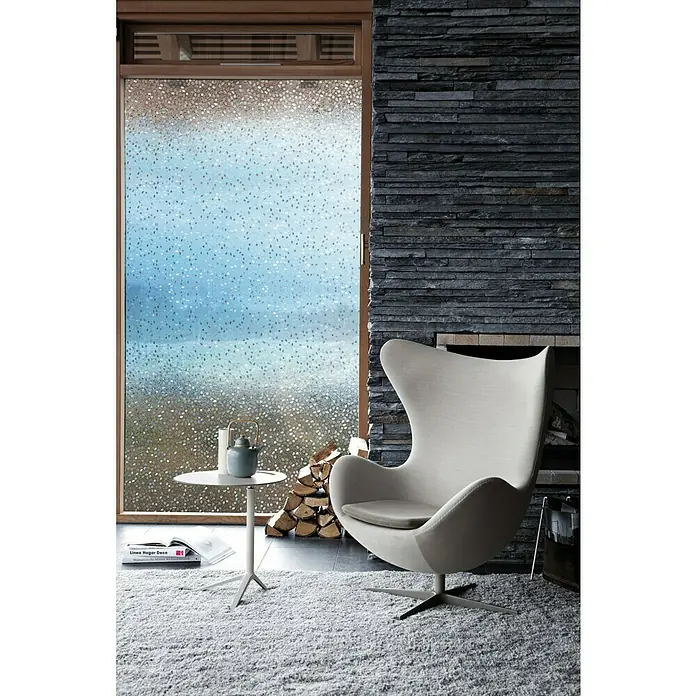 Lámina para ventana Gofrado Fix Rice Mini - 92 cm x 1,5 m, Transparente - Un elegante salón con una silla moderna, una mesa pequeña y una película decorativa para ventanas para mayor privacidad.