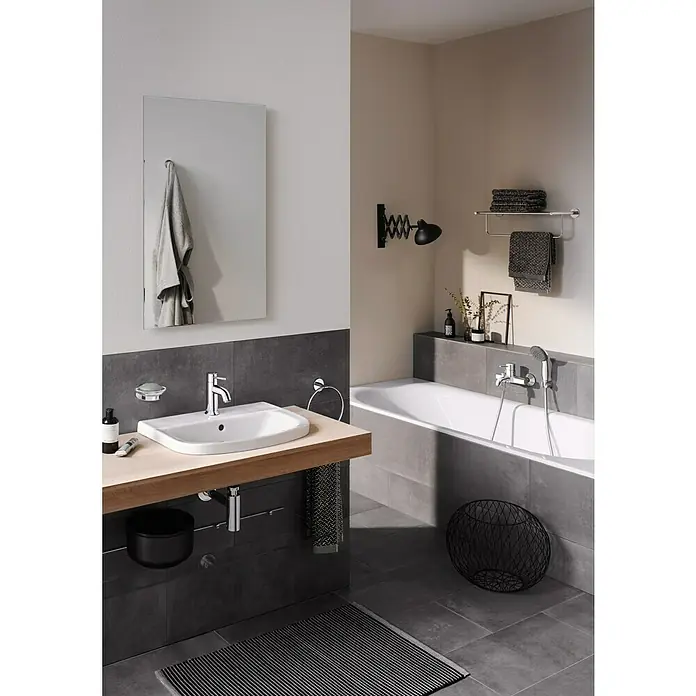Grohe Essentials Ersatz-Seifenschale - Glas, Transparent - Badezimmer-Interieur mit modernem Waschbecken, Armatur und Spiegel. Die Holzplatte und grauen Fliesen verleihen dem Raum eine elegante Note.