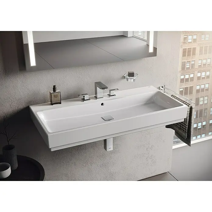 Grohe Essentials Cube Becher- & Seifenhalter - Chrom, Glänzend - Bild eines modernen, rechteckigen Waschbeckens mit Chromarmaturen, Seifenspender und Handtuchhalter in einem stilvollen Badezimmer.