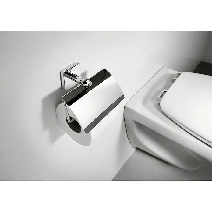 Roca Victoria Portarrollos papel higiénico - Cromo, Metal - Un moderno portarrollos de papel higiénico cromado con un rollo blanco limpio y una tapa elegante, junto a un inodoro.