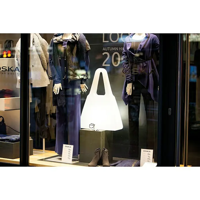 8 Seasons Design Shining LED-Dekoleuchte Bag - 6 W, Weiß, L x B x H: 19 x 55 x 75 cm - Eine OSKA-Schaufensterpuppe mit eleganter Herbstmodekollektion, einschließlich eines weißen Shoppers, präsentiert in einem stilvollen Arrangement.
