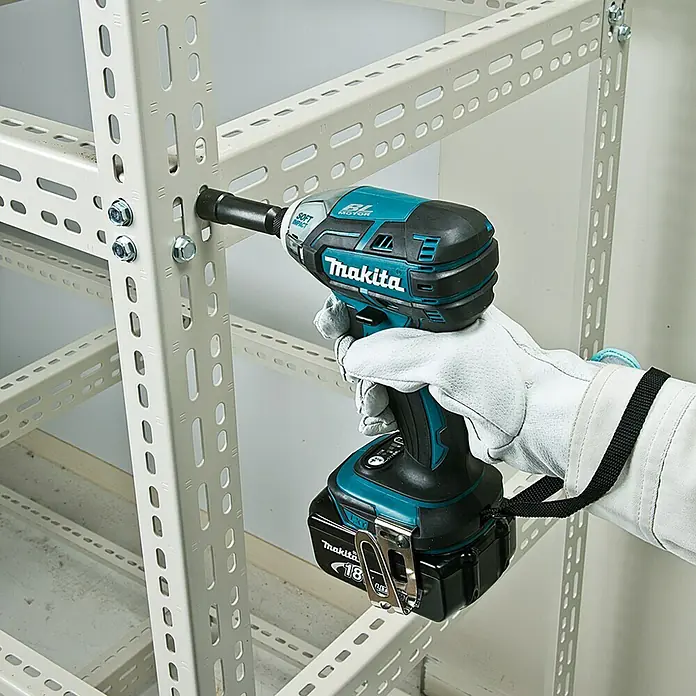 Makita LXT 18V Akku-Impulsschrauber DTS141RTJ - 18 V, 2 Akkus, 5 Ah, 40 Nm - Nahaufnahme eines Akku-Schlagschraubers von Makita beim Festziehen einer Schraube an einem Metallregal.