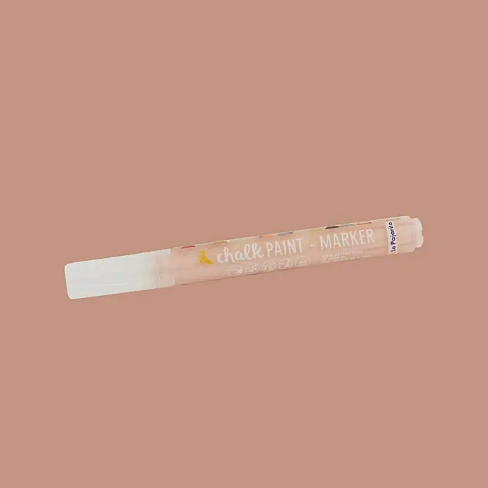 La Pajarita Marcador para ropa Chalk Paint Marker - Peach, 6 ml, Mate - Primer plano de un rotulador de pintura de tiza con tapa blanca sobre un fondo marrón. Ideal para proyectos de arte.