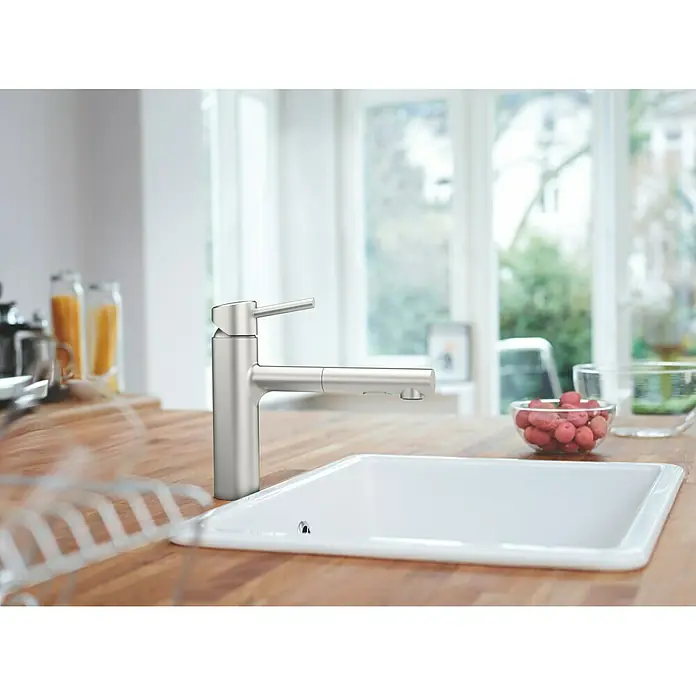 Grohe Concetto Spültischarmatur - Edelstahl, Matt, Anzahl Strahlarten: 2 Stk. - Nahaufnahme eines eleganten Küchenarmatur mit ausziehbaren Brause vor einem hellen Küchenfenster.