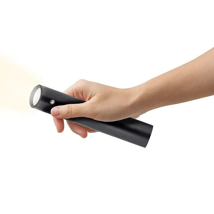 Akku-Pendelleuchte ausziehbar 37 - 163 cm - 7,5 cm, Schwarz, Warmweiß - Eine Hand hält eine eingeschaltete schwarze Taschenlampe, die einen Lichtstrahl erzeugt. Ideal für den Einsatz im Dunkeln.