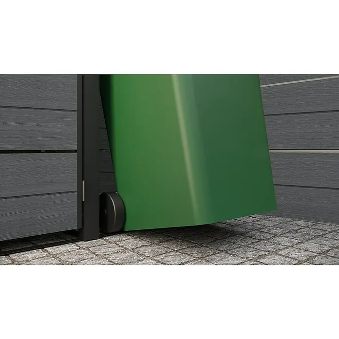 Keter Erweiterung für Mülltonnenbox Hide Away Extension - Passend für: Keter Mülltonnenbox Hide Away, Grau - Detailaufnahme eines grünen Abfallbehälters mit Rollen, der neben einer grauen Holzwand auf einem gepflasterten Untergrund steht.