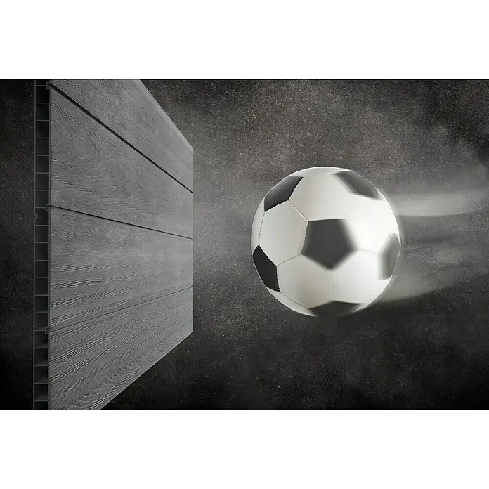 Keter Gerätehaus Newton Plus 759 - Außenmaß inkl. Dachüberstand (B x T): 230 x 287 cm, Kunststoff, Schiefergrau - Ein Fußball fliegt auf eine graue Holzwand zu, die das robuste und stilvolle Design dieses Produkts hervorhebt.