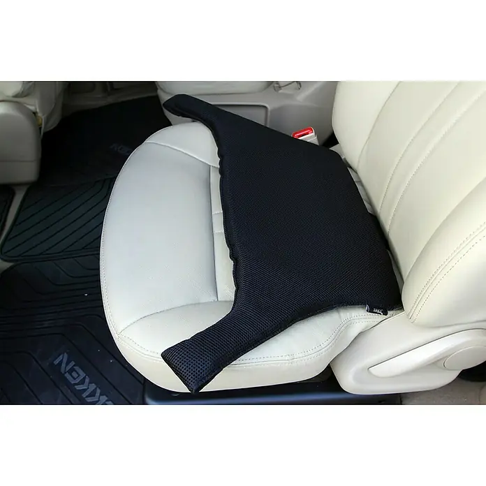 Adaptador de cinturón para embarazadas - Negro - Un cojín negro para asiento de coche con soporte lumbar sobre un asiento de cuero crema. Ofrece comodidad y soporte para viajes largos.