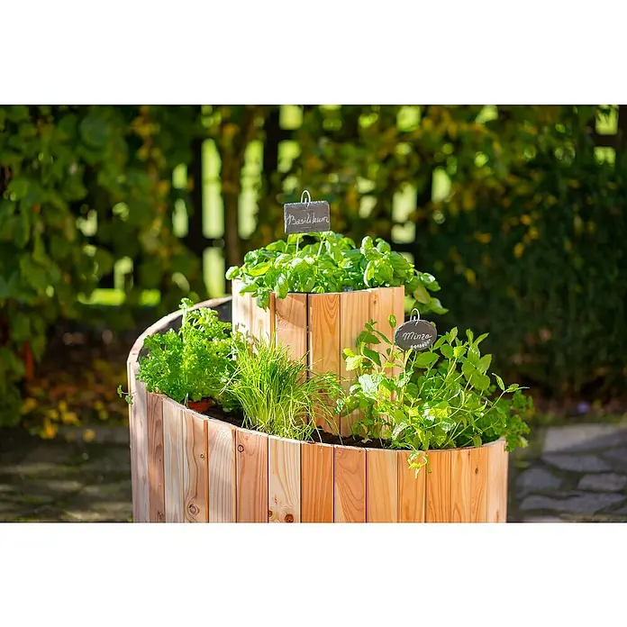 Westmann Kräuterspirale Luise - Ø x H: 55 x 77 cm - Ein Kräuterbeet aus Holz mit Basilikum, Minze, Schnittlauch und Petersilie. Das Beet steht im Garten und ist gut beschriftet.