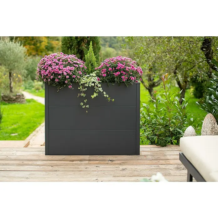 Westmann Pflanzkasten Talus XL - L x B x H: 25 x 100 x 77 cm, Metall, Anthrazit - Das Bild zeigt einen modernen, grauen Pflanzkasten mit üppigen pinkfarbenen Blumen und grünen Ranken, der auf einer Holzterrasse steht.