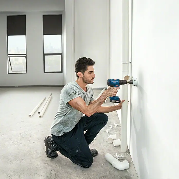 Bosch Professional AMPShare 18V Akku-Bohrschrauber GSR 18V-21 L-Boxx - 18 V, 2 Akkus, 2 Ah, 55 Nm - Handwerker bohrt mit einem Akku-Bohrschrauber ein Loch in eine Wand. Das Werkzeug ist ideal für Arbeiten im Innenbereich.