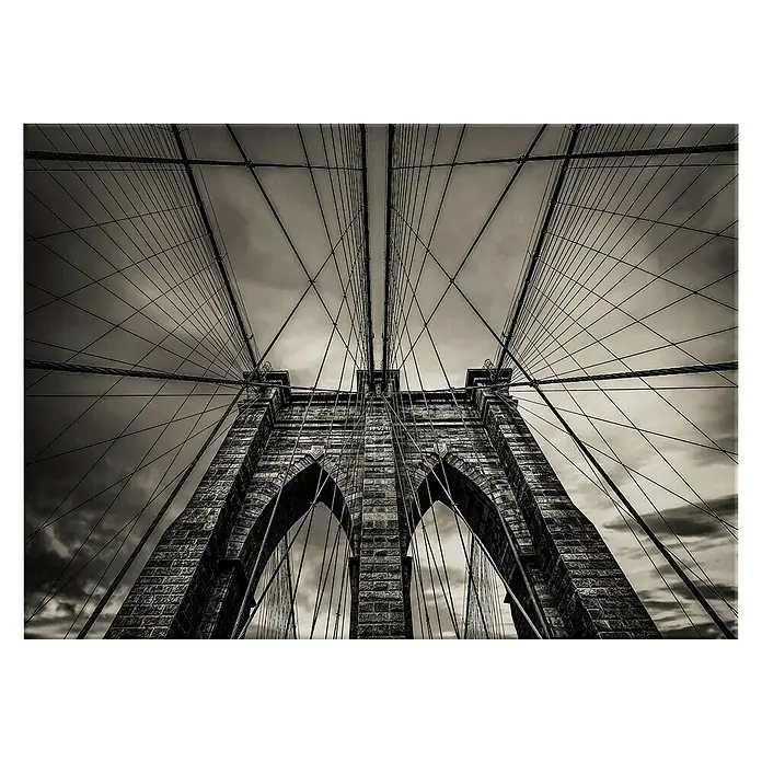 Leinwandbild - Brooklyn, B x H: 113 x 85 cm - Schwarz-Weiß-Foto der Brooklyn Bridge, die sich mit ihren Kabeln und Steinbögen majestätisch gegen den Himmel erhebt.
