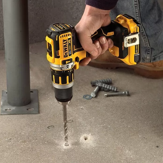 DeWalt XR 18V Taladro atornillador percutor de batería DCD795D2 - 18 V, 2 baterías, 2 Ah, 60 Nm - Una persona utiliza un taladro sin escobillas DeWalt 20V MAX XR amarillo y negro para hacer un agujero en hormigón.