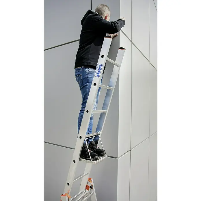 Krause Trittablage - L x B x H: 450 x 340 x 70 mm - Eine Person steht auf einer Krause Leiter und arbeitet an einer Wand. Die Leiter ist aus Aluminium und hat eine Plattform.