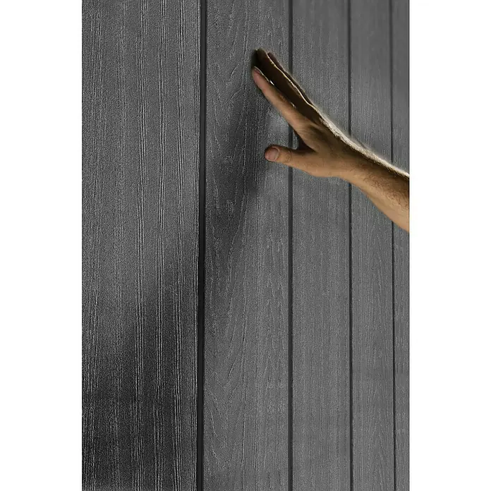 Keter Gerätehaus Newton Plus 759 - Außenmaß inkl. Dachüberstand (B x T): 230 x 287 cm, Kunststoff, Schiefergrau - Nahaufnahme eines grauen Holzpaneels mit einer Hand, die die Textur berührt. Das Paneel zeigt eine deutliche Holzmaserung.