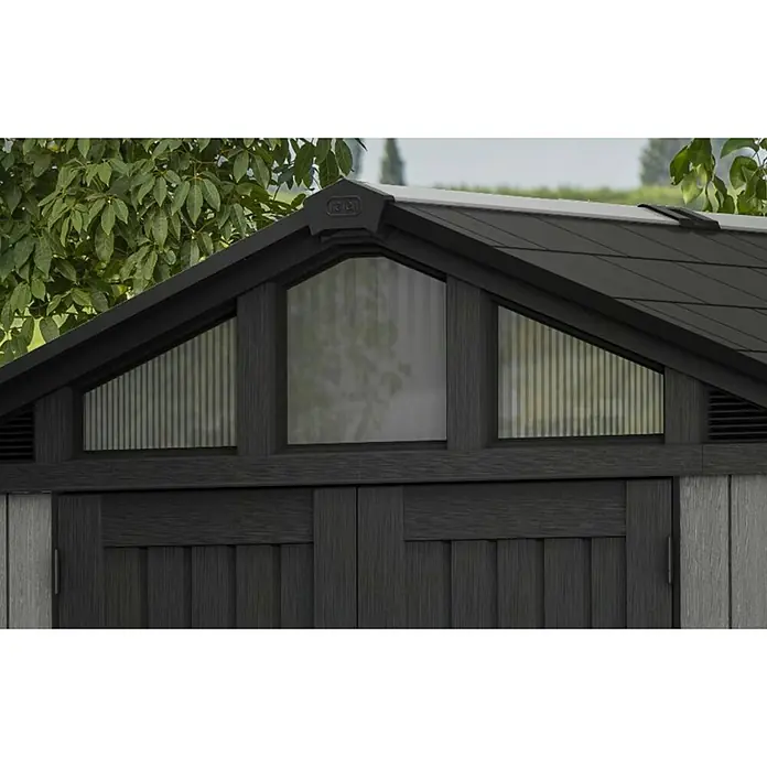 Keter Gerätehaus Stronghold 10x8 - Außenmaß inkl. Dachüberstand (B x T): 304 x 243 cm, Kunststoff, Grau - Nahaufnahme des Giebels eines Gerätehauses mit Fenster, das Licht hereinlässt. Das dunkle Dach und die Holzstruktur sind gut erkennbar.