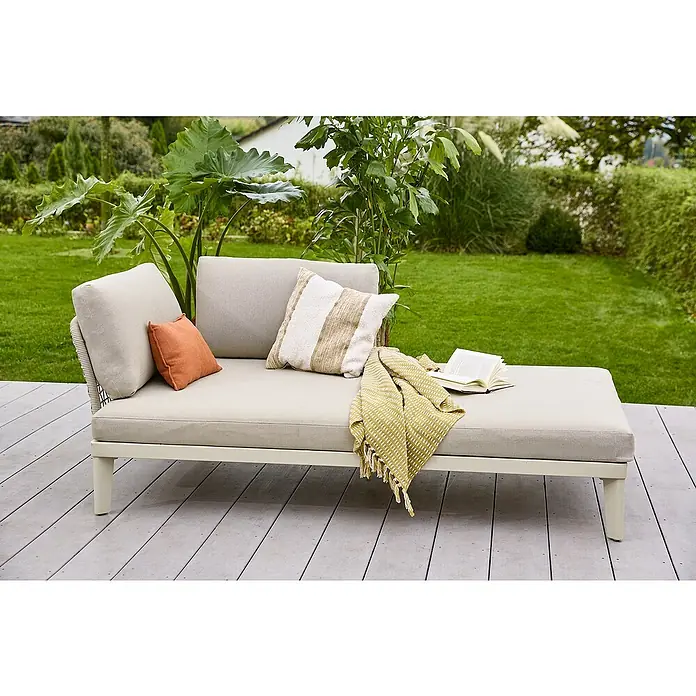 Sunfun Solo Rope Chaise lounge - An x Pr: 194 x 114,5 cm, Metal, Gris - Primer plano de una cómoda tumbona de color claro con almohadas y una manta en un patio, con una exuberante vegetación al fondo.