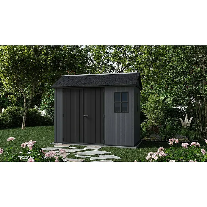 Keter Gerätehaus Newton Plus 759 - Außenmaß inkl. Dachüberstand (B x T): 230 x 287 cm, Kunststoff, Schiefergrau - Eine dunkle Gartengerätebox mit Fenster und Doppeltür steht im Garten mit Blumen und Bäumen herum.