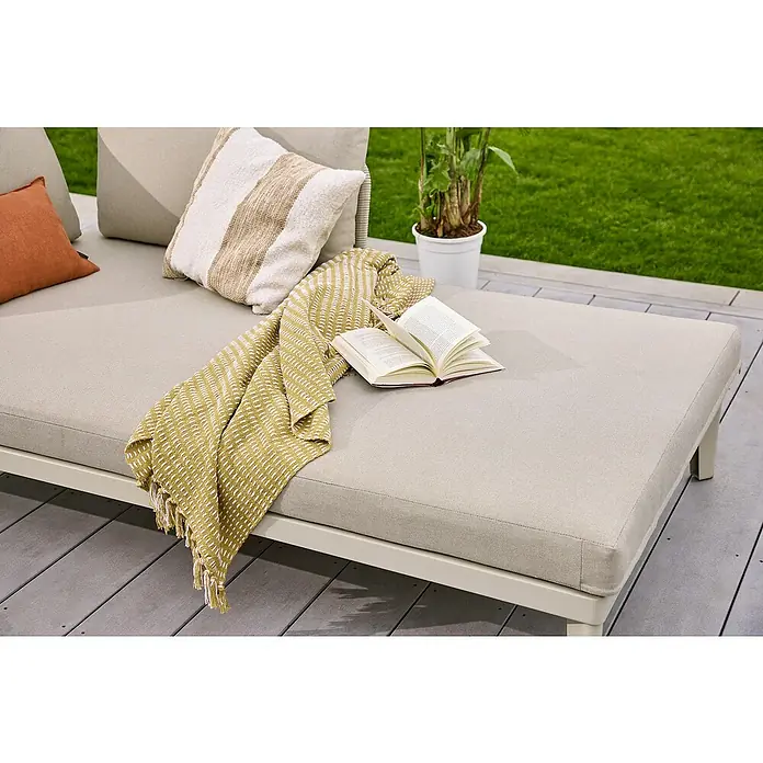 Sunfun Solo Rope Lounge-Ottomane - Light-Greige, Metall - Nahaufnahme einer stilvollen Outdoor-Couch mit Kissen, Decke und einem offenen Buch, ideal zum Entspannen im Freien.