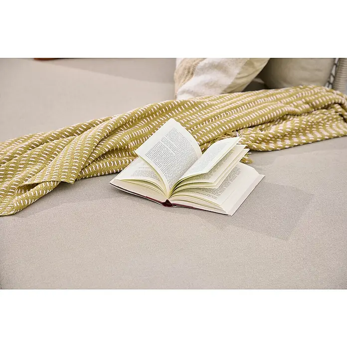 Sunfun Solo Rope Chaise lounge - An x Pr: 194 x 114,5 cm, Metal, Gris - Un libro abierto reposa en un sofá beige junto a una manta a rayas amarilla y blanca, creando un ambiente acogedor perfecto para leer.