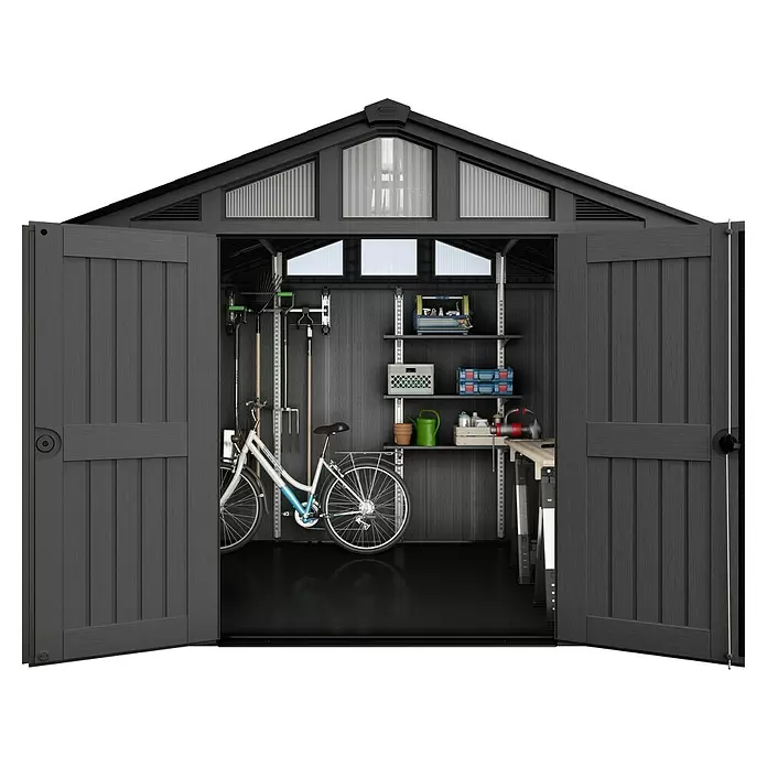Keter Gerätehaus Stronghold 10x8 - Außenmaß inkl. Dachüberstand (B x T): 304 x 243 cm, Kunststoff, Grau - Dunkelgraues Gartenhaus mit offenen Türen, das einen organisierten Innenraum mit Regalen, einem Fahrrad, Gartengeräten und einer Werkbank zeigt.