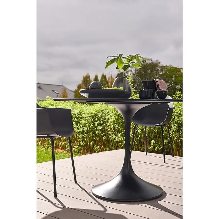 Gartentisch rund Black Series - Ø x H: 120 x 74 cm, Verbundwerkstoff, Schwarz - Schwarzer Esstisch mit Tulpenfuß und zwei Stühlen auf einer Terrasse, dekoriert mit Schale, Pflanze und Geschirr.