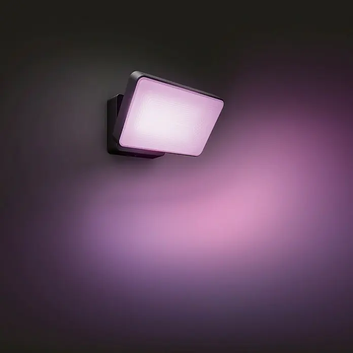 Philips Hue LED-Strahler White & Color Ambiance - 15 W, L x B x H: 22 x 16 x 15,3 cm, Schwarz, RGBW - Aufnahme einer Philips Hue LED-Wandleuchte mit farbigem Licht, die einen dramatischen Effekt erzeugt. Diese Lampe ist ideal für Außenbereiche.