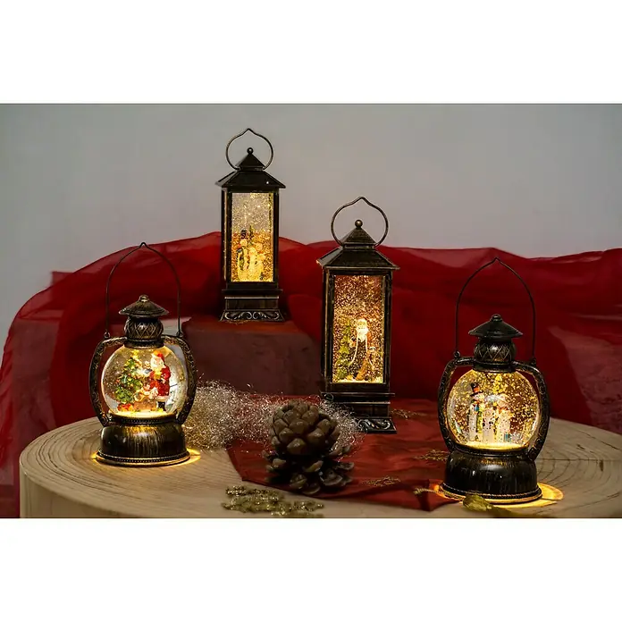 Konstsmide LED-Schneelaterne Schneemannfamilie - Innen, Braun, 12,7 x 10,8 x 20 cm, Schneemann, Batteriebetrieben - Nahaufnahme von vier dekorativen Weihnachtslaternen mit Schneekugeln mit weihnachtlichen Motiven auf einem Holztisch.
