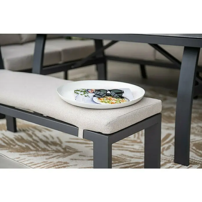 Garden Impressions Loungemöbel-Set Vasano - 4 -tlg., Aluminium, Keramik, Polyester, Links, Schwarz/Beige - Nahaufnahme eines modernen grauen Gartenbank mit beigem Kissen, auf der eine weiße Schale mit einer Zeitschrift und einer Sonnenbrille liegt.