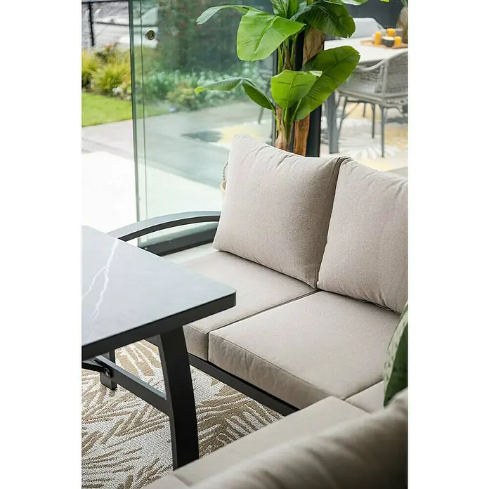 Garden Impressions Loungemöbel-Set Vasano - 4 -tlg., Aluminium, Keramik, Polyester, Links, Schwarz/Beige - Nahaufnahme eines Outdoor-Sofas mit hellen Kissen und einem dunklen Tisch mit marmorierter Platte auf einem gemusterten Teppich.