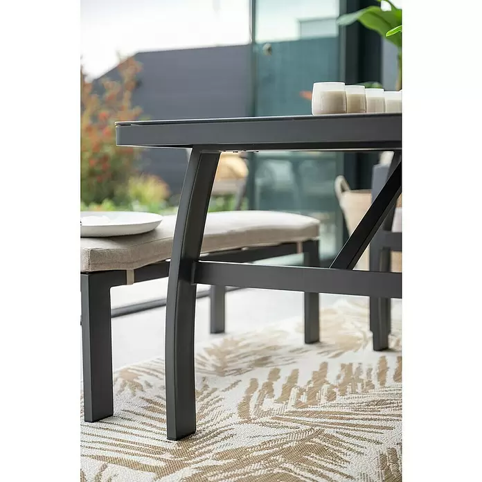 Garden Impressions Loungemöbel-Set Vasano - 4 -tlg., Aluminium, Keramik, Polyester, Links, Schwarz/Beige - Dunkelgrauer Outdoor-Esstisch und Bänke mit Polstern auf gemustertem Teppich.