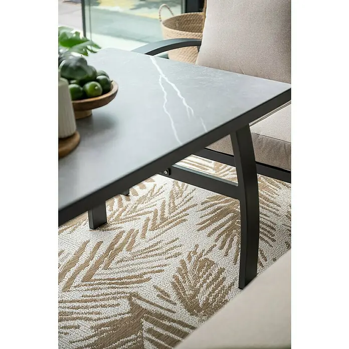 Garden Impressions Loungemöbel-Set Vasano - 4 -tlg., Aluminium, Keramik, Polyester, Links, Schwarz/Beige - Nahaufnahme eines Gartentisches mit grauer Marmorplatte und schwarzem Metallgestell, stehend auf einem Teppich mit Blattmuster.