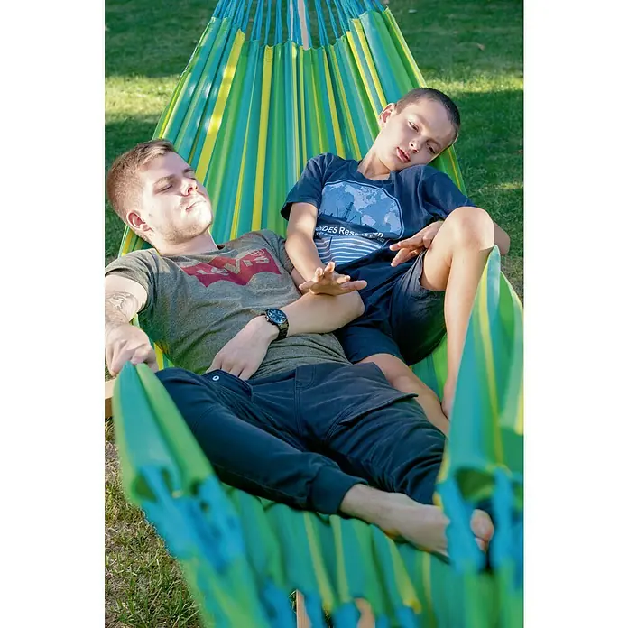 La Siesta Hängematte Brisa - L x B: 350 x 160 cm, Lime - Zwei Personen entspannen in einer Hängematte mit gelben und grünen Streifen. Die Hängematte ist bequem und lädt zum Verweilen ein.