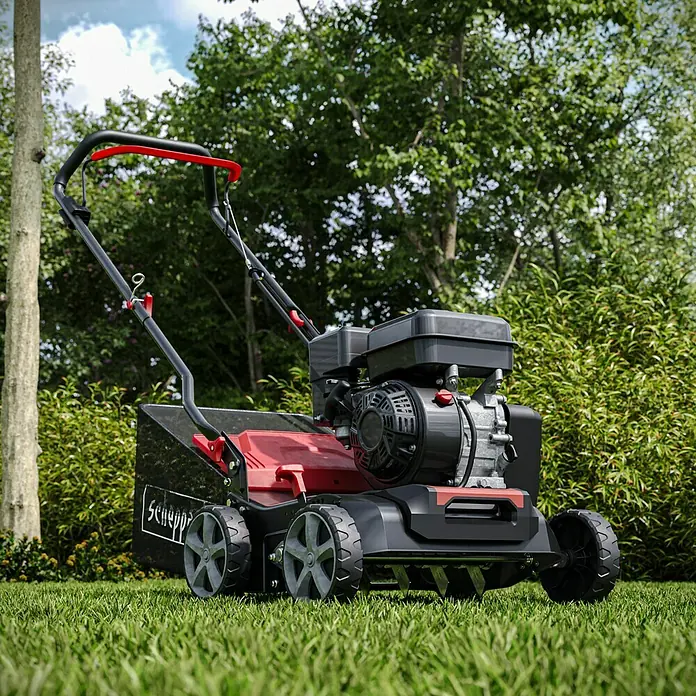 Scheppach Escarificador de gasolina SC55P - 4 kW, Anchura de trabajo: 40 cm - Primer plano de un aireador de césped Scheppach sobre un césped, diseñado para el cuidado del césped en el jardín.