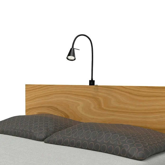 Briloner Foco de pared LED para cama Comfort Light - Negro, 4 W - Una moderna lámpara de pared LED negra montada sobre un cabecero de madera con almohadas, perfecta para dormitorios o habitaciones de hotel.