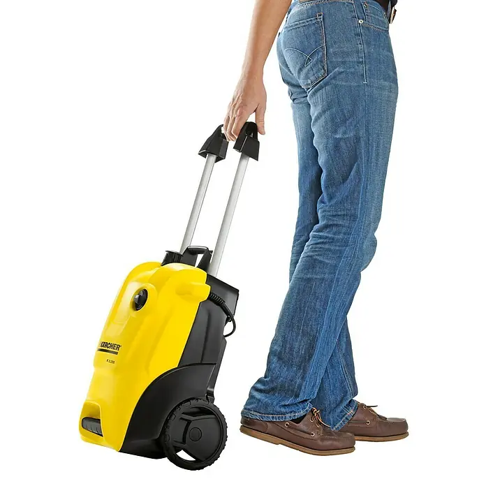 Kärcher Hochdruckreiniger K4 Pure Home - 1.800 W, Max. Druck: 130 bar, Fördermenge: 420 l/h - Ein gelber Kärcher Hochdruckreiniger K3.200 wird von einer Person auf einem weißen Hintergrund gezogen.