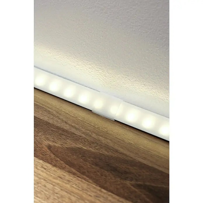 Paulmann Delta Profil Cover - Kunststoff - Nahaufnahme einer LED-Leiste, die unter einem Schrank oder Regal montiert ist und warmes, stimmungsvolles Licht spendet.\n