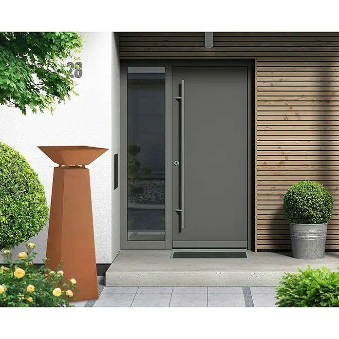 Jabo-Design Dekosäule mit Schale - Edelrost - Graue Haustür mit Seitenteil und langem Griff in moderner Hausfassade. Der Eingangsbereich ist einladend gestaltet.