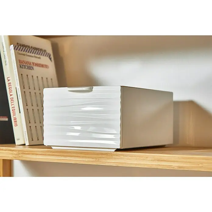 Schubladenbox QBox Wave Mini - L x B x H: 21 x 15,5 x 10,5 cm, Weiß, Anzahl Schubladen: 1 Stk. - Nahaufnahme einer weißen Schachtel mit gewelltem Design auf einem Holzregal, neben Büchern platziert.