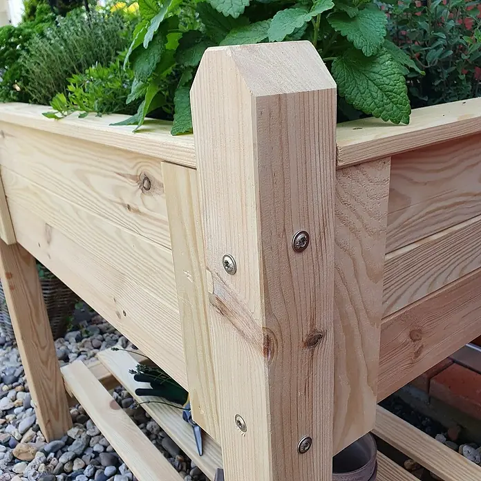 Promadino Hochbeet - 90 x 60 x 84,5 cm, Holz, Natur - Detailansicht eines Hochbeets aus hellem Holz mit abgerundeten Pfosten und Schrauben, gefüllt mit grünen Kräutern.