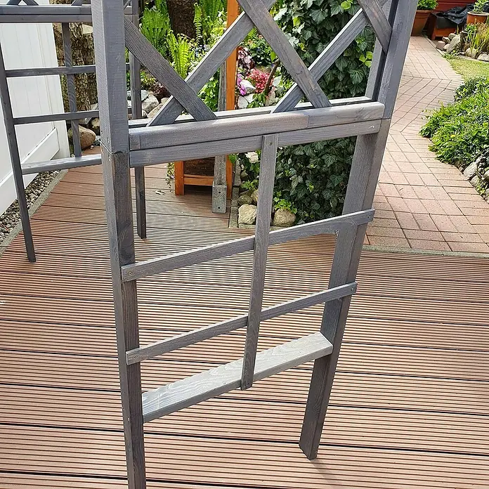 Promadino Pergola Ben - 60 x 200 x 210 cm, Grau, Holz - Nahaufnahme einer grauen Gartenlaube aus Holz auf einer Holzterrasse, die einen malerischen Garten im Hintergrund rahmt.