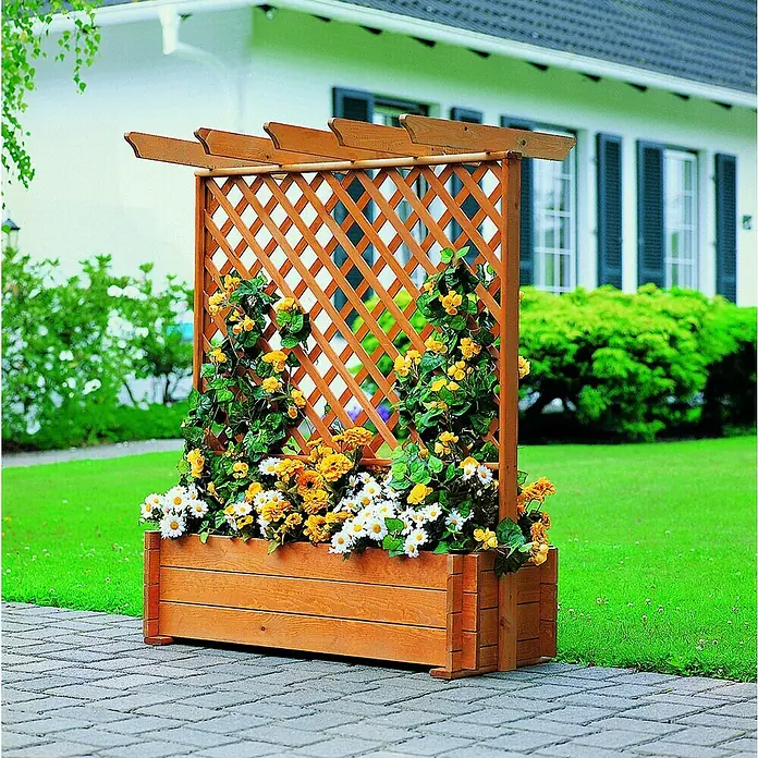 Promadino Pflanzkasten mit Pergola - Außenmaß (L x B x H): 140 x 64,5 x 102 cm, Holz, Honigbraun - Holz-Pflanzkasten mit Rankgitter und bunten Blumen auf gepflastertem Weg vor einem Haus mit grüner Wiese.