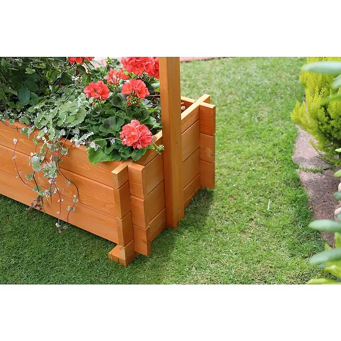 Promadino Pflanzkasten mit Pergola - Außenmaß (L x B x H): 140 x 64,5 x 140 cm, Holz, Honigbraun - Ein Holzkasten mit leuchtend roten Geranien und grünen Pflanzen, der auf einem Rasen steht, bietet eine farbenfrohe Gartendekoration.