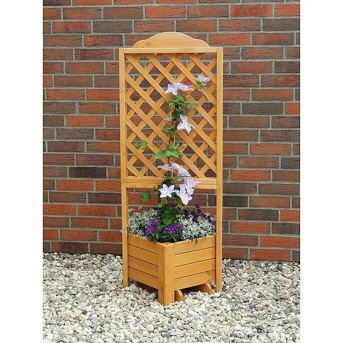 Promadino Pflanzkasten Romantica - Außenmaß (L x B x H): 140 x 38 x 38 cm, Holz, Honigbraun - Das Bild zeigt eine Pflanzkasten-Rankgitter-Kombination aus Holz mit blühenden Pflanzen vor einer Backsteinmauer.
