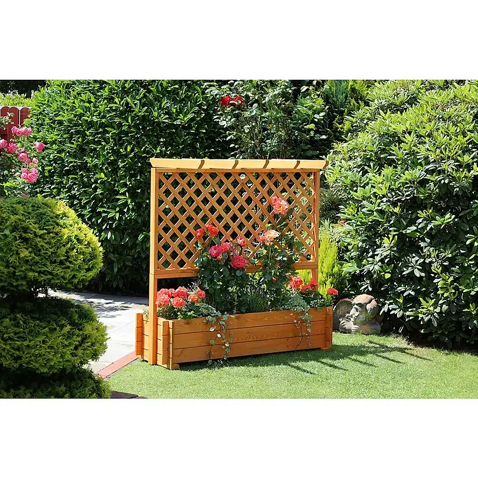 Promadino Pflanzkasten mit Pergola - Außenmaß (L x B x H): 140 x 64,5 x 140 cm, Holz, Honigbraun - Ein hölzernes Hochbeet mit Rankgitter, bepflanzt mit roten und rosafarbenen Blumen, steht im Garten vor grünen Büschen.