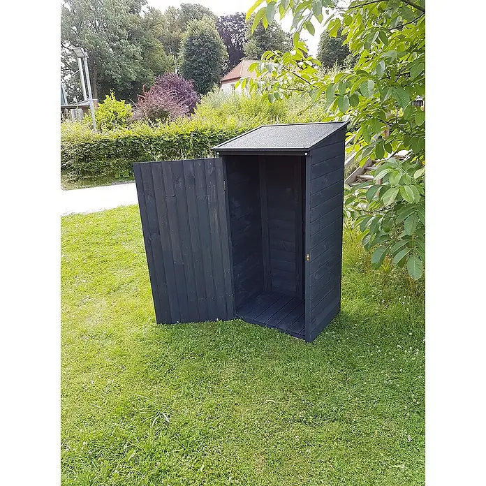 Promadino Geräteschrank Speyer - Holz, Anthrazit - Ein dunkler Holzschuppen mit geöffneter Tür steht auf einem Rasen, umgeben von Bäumen und Sträuchern, ideal für Gartengeräte.