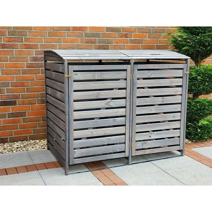 Promadino Mülltonnenbox Vario III -  - Eine graue, doppelte Mülltonnenbox aus Holz steht vor einer Ziegelmauer. Sie bietet eine stilvolle Lösung zur Mülltonnenaufbewahrung.